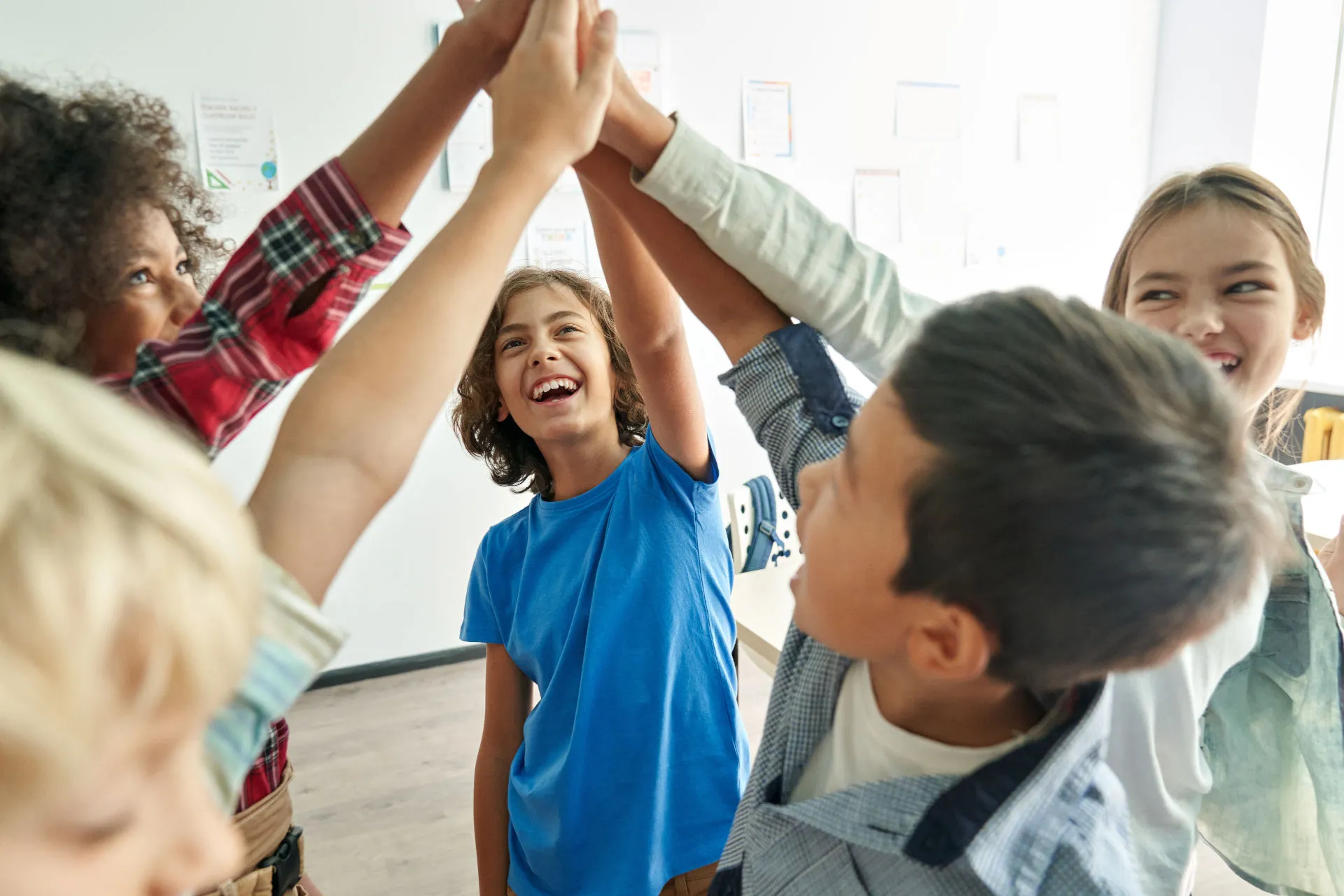 Fünf Schüler*innen geben sich einen High five und lachen