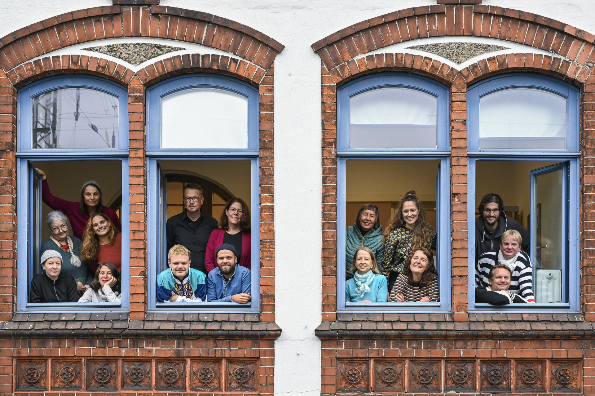 Die Mitarbeitenden der Freiwilligenagentur gucken den Betrachter aus dem Fenster der Agentur heraus an.